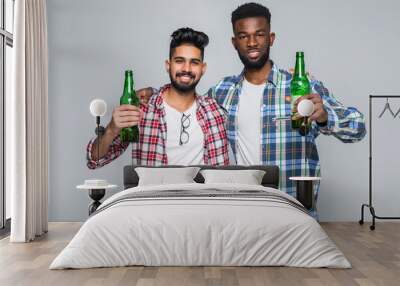 Portrait of a two happy young men best friends toasting with beer bottles celebrating isolated over white background Wall mural